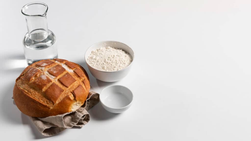 Pain intégral, farine, eau et sel sur table blanche