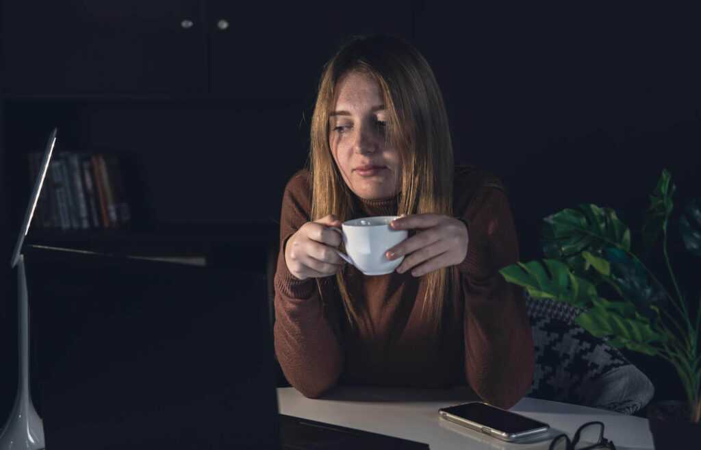 Femme fatiguée buvant du café devant son ordinateur la nuit