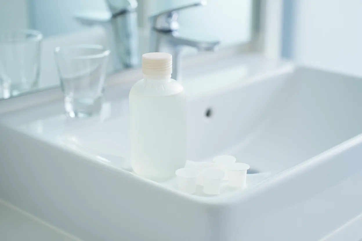 Bouteille d’eau oxygénée sur lavabo blanc.